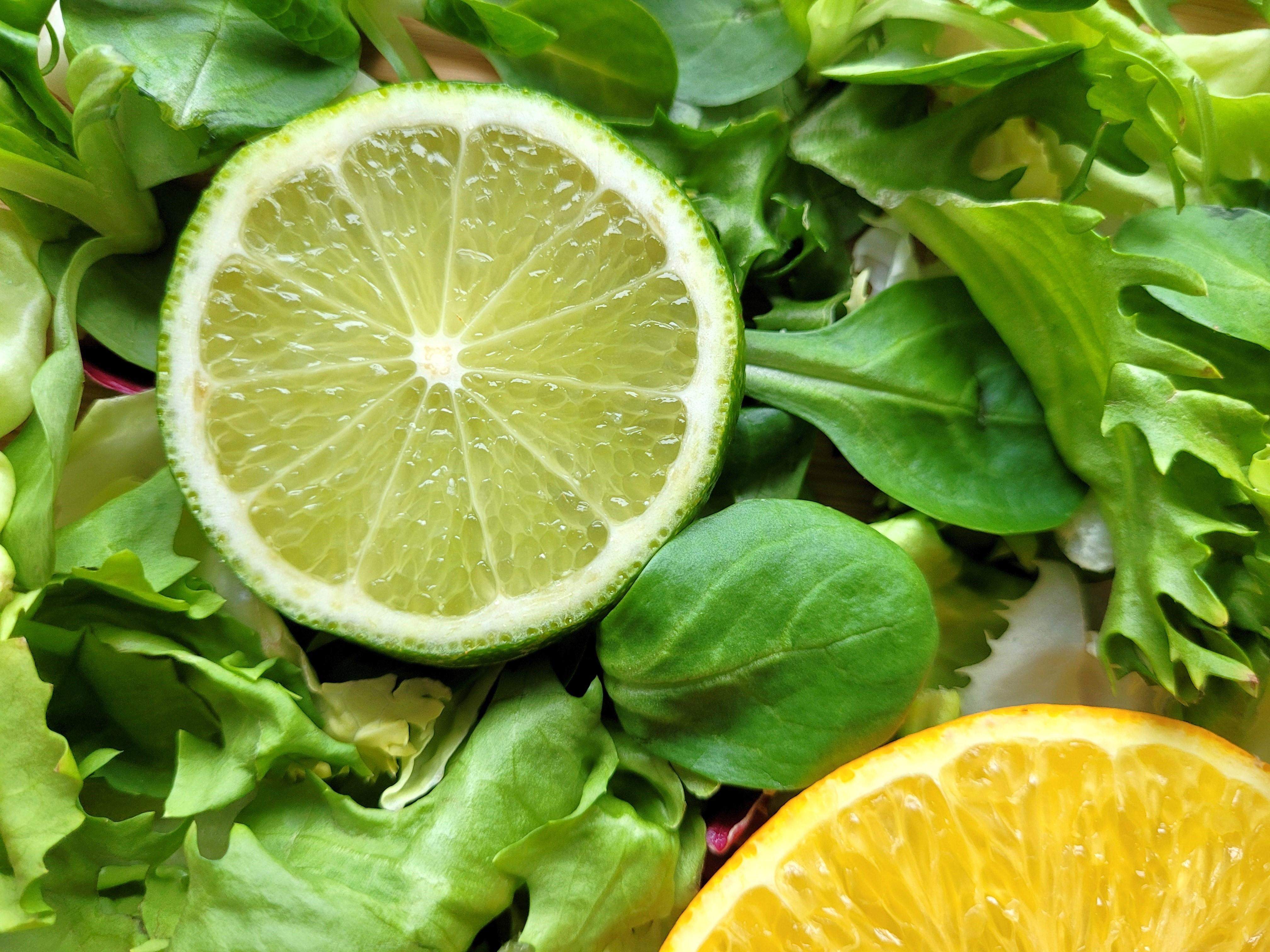 Zdjęcie na którym widać limonkę, pomarańczę i zielone warzywa liściaste