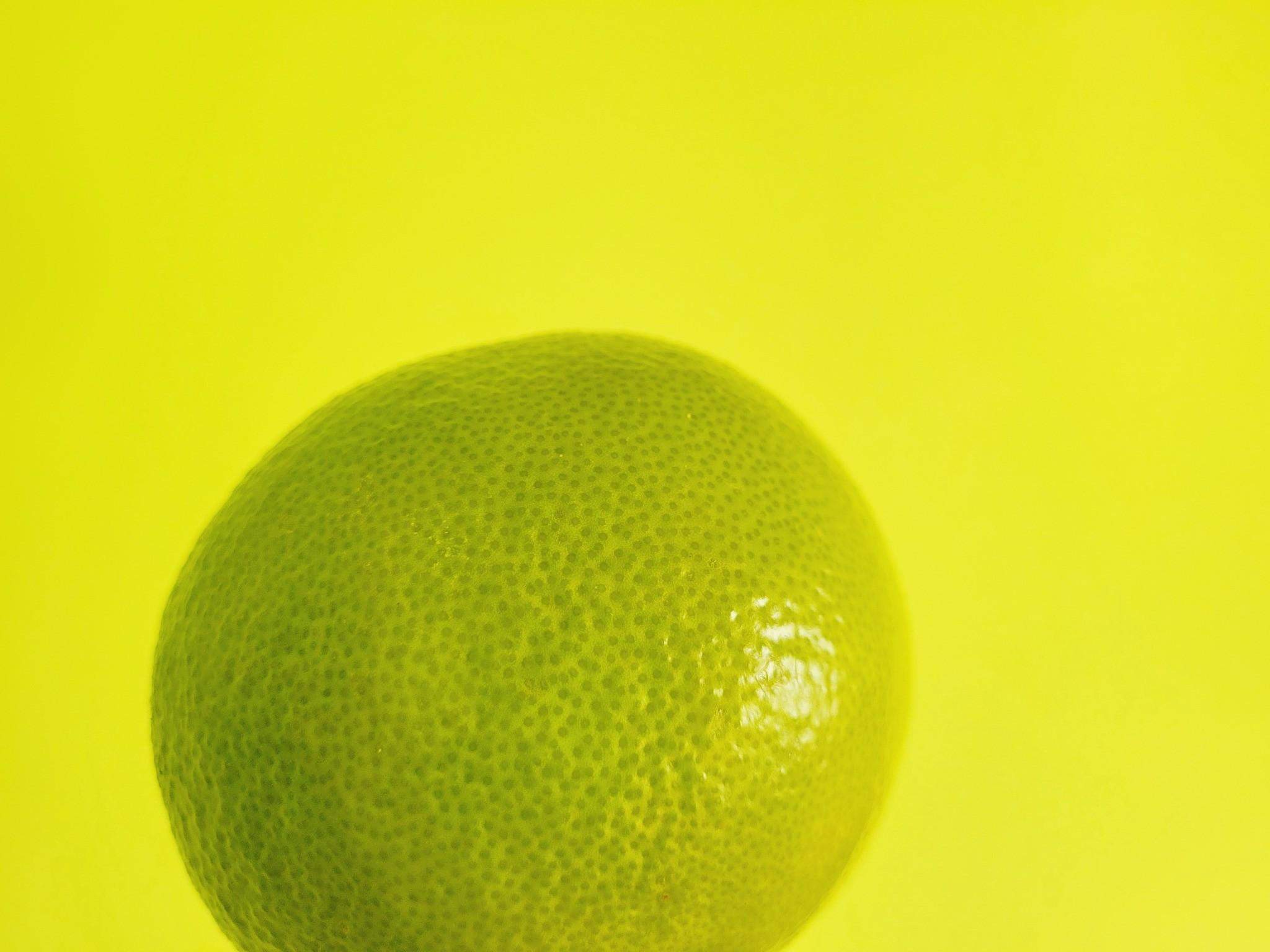 Zielony grejpfrut na żółtym tle minimalistyczna fotografia owocu tropikalnego