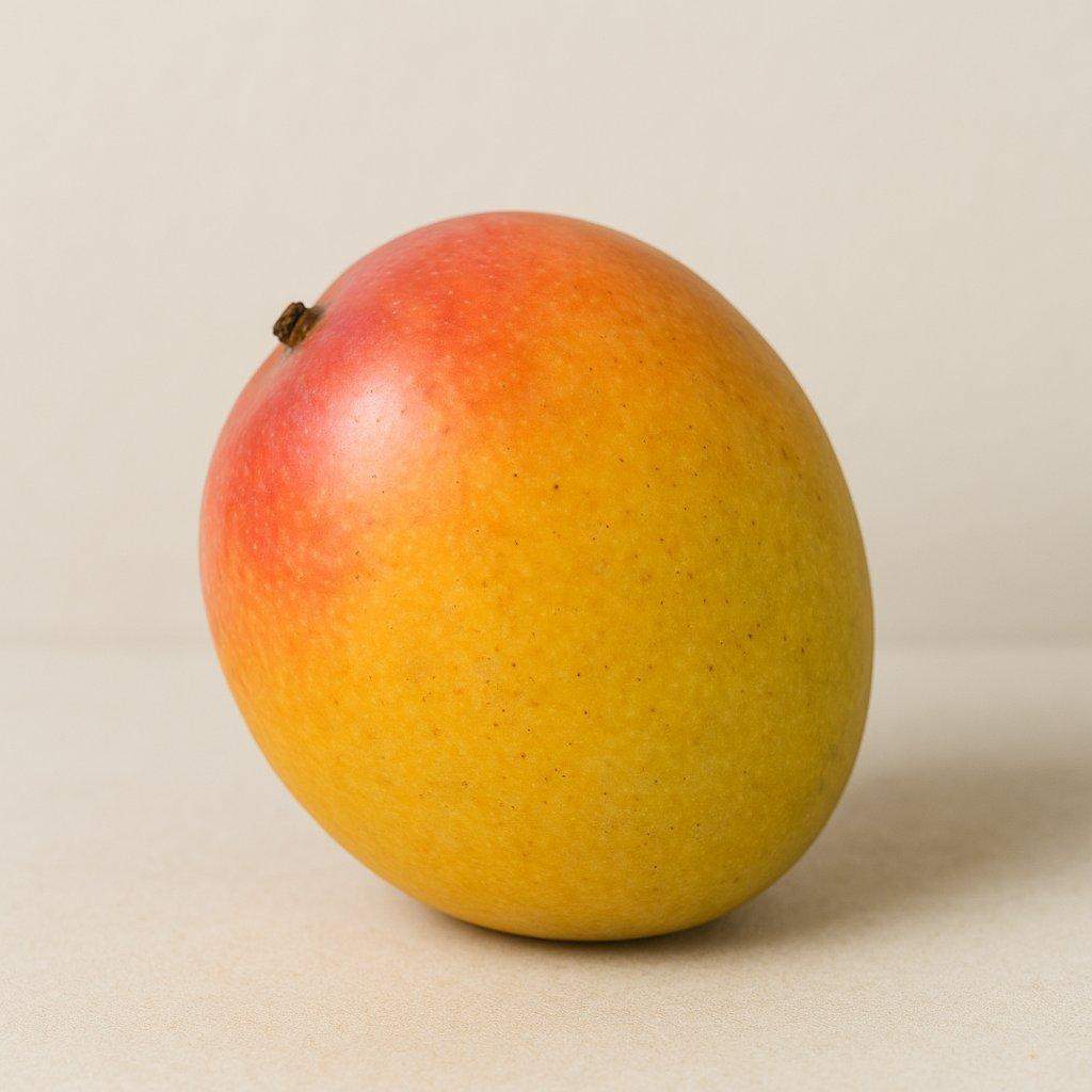 Dojrzałe mango o żółto-pomarańczowej skórce, sfotografowane w naturalnym świetle na neutralnym tle. Realistyczne zdjęcie bez retuszu, ukazujące świeżość i naturalny kolor owocu.